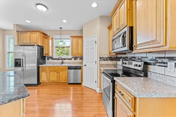 a kitchen with stainless steel appliances granite countertop a sink a stove and refrigerator
