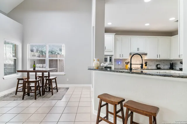 a kitchen with a dining table chairs and granite counter tops