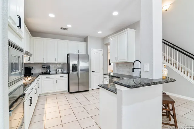a kitchen with stainless steel appliances granite countertop a refrigerator sink and white cabinets