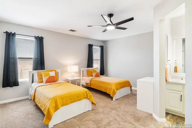 a bedroom with two beds and ceiling fan