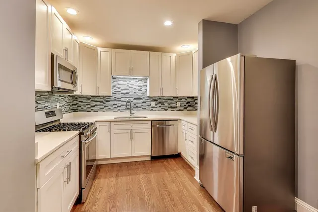 a kitchen with stainless steel appliances granite countertop a refrigerator sink and white cabinets