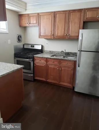 a kitchen with granite countertop a refrigerator a stove a sink dishwasher and wooden cabinets