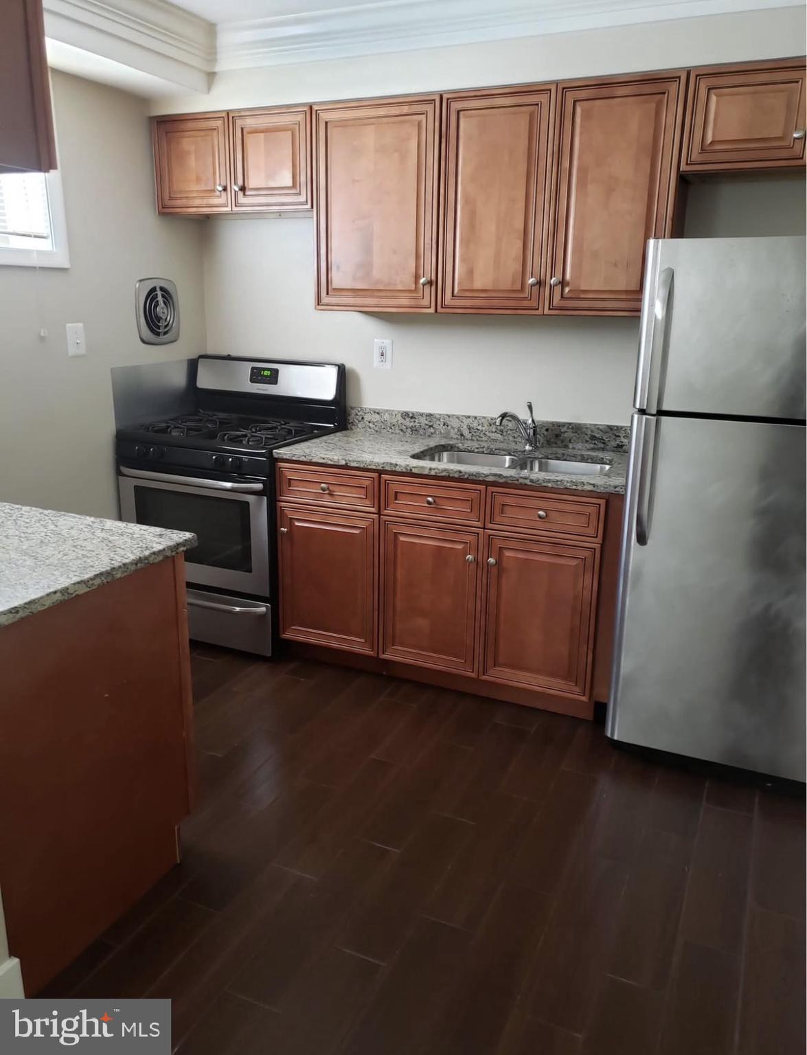 4102 Queensbury Road Hyattsville, MD 20781 - Photo 1 of 6 a kitchen with granite countertop a refrigerator a stove a sink dishwasher and wooden cabinets