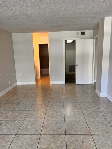 a view of an empty room with wooden floor and a bathroom