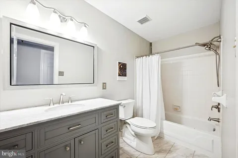 a bathroom with a toilet a sink a mirror a bathtub and shower