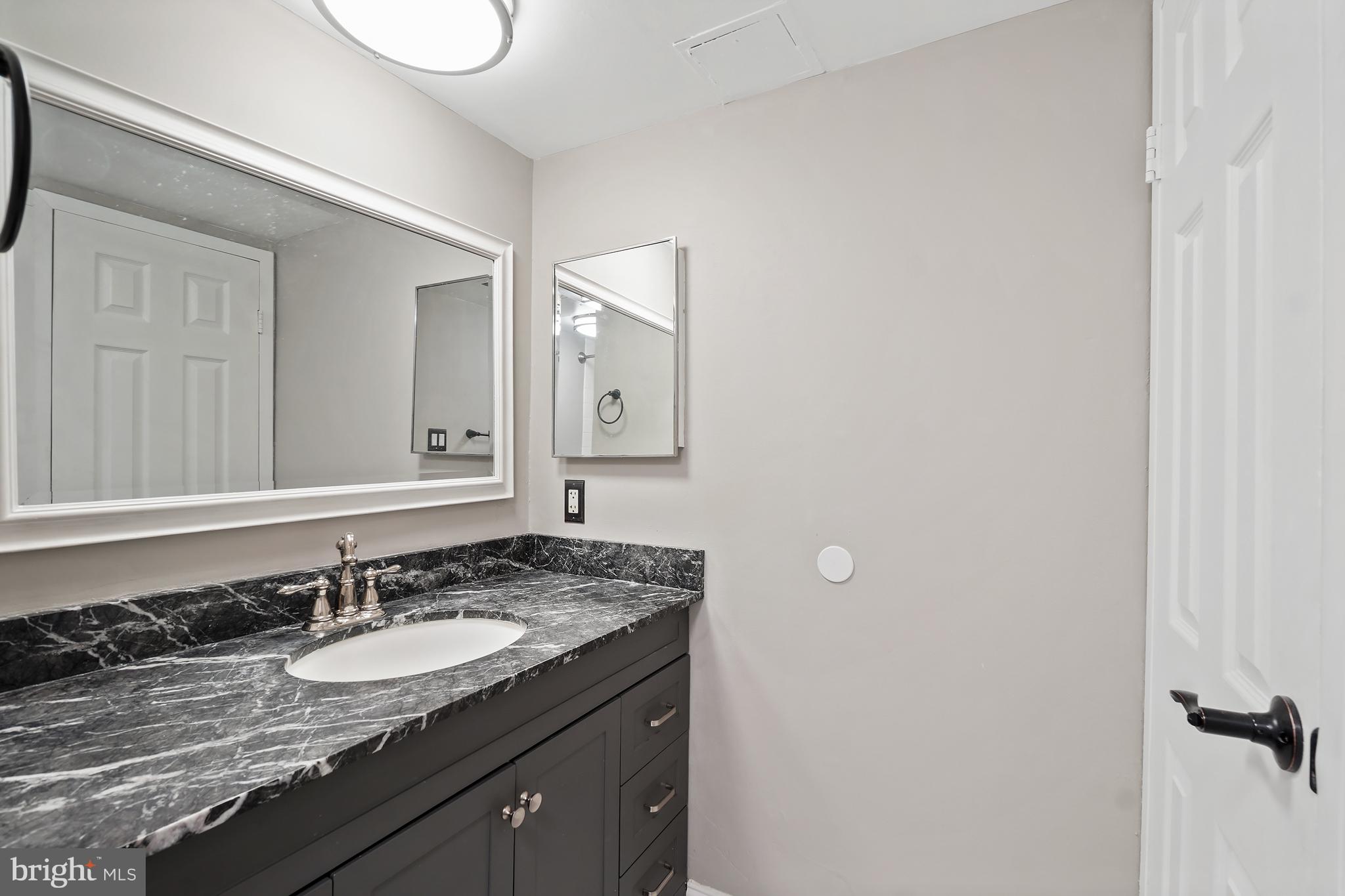 8487 Greenbelt Road Greenbelt, MD 20770 - Photo 18 of 29 a bathroom with a granite countertop sink and a mirror