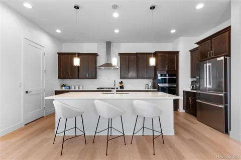 a kitchen with stainless steel appliances a sink a stove a refrigerator cabinets and wooden floor