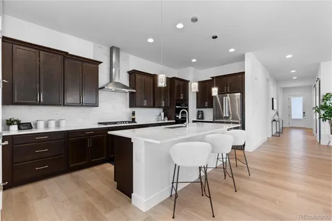 a kitchen with stainless steel appliances kitchen island granite countertop a sink a stove top oven a counter space and cabinets