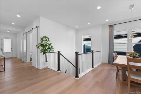 a living room with stainless steel appliances furniture wooden floor and a view of kitchen