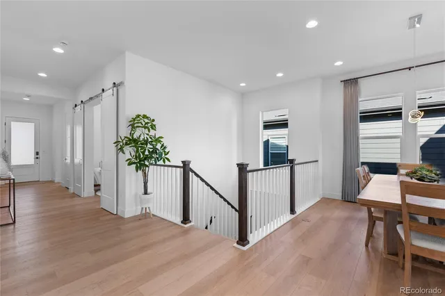 a living room with stainless steel appliances furniture wooden floor and a view of kitchen