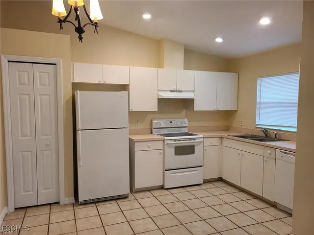 a kitchen with white cabinets a sink appliances and a counter top space