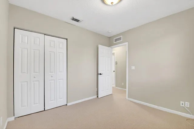 an empty room with a chandelier fan and windows