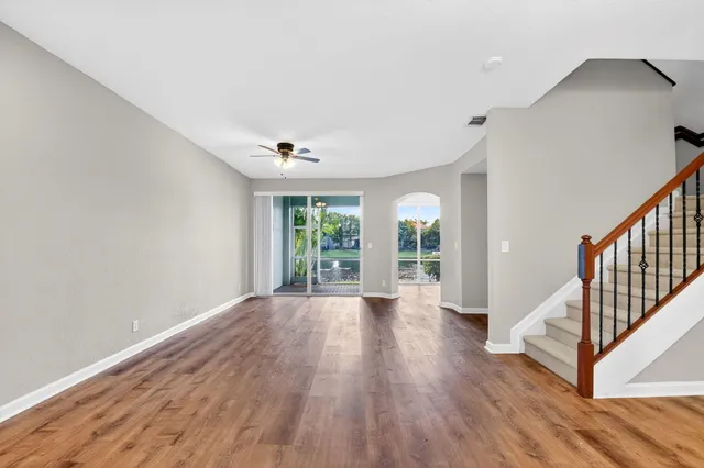 a view of empty room with wooden floor and fan
