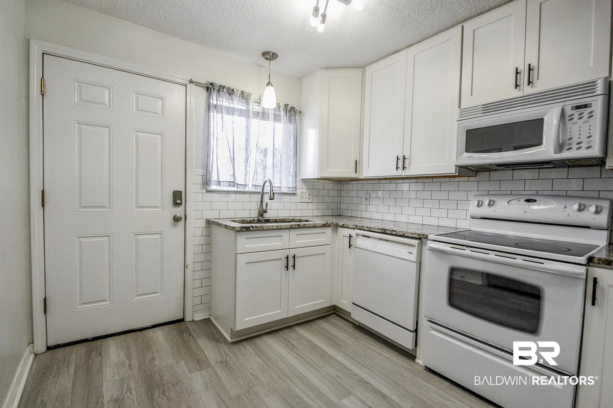 25957 Canal Road, Unit 203 Orange Beach, AL 36561 - Photo 5 of 28 Kitchen with white appliances, light wood-type flooring, light stone countertops, tasteful backsplash, and hanging light fixtures