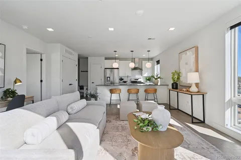 a living room with stainless steel appliances kitchen island granite countertop a couch and a dining table with wooden floor