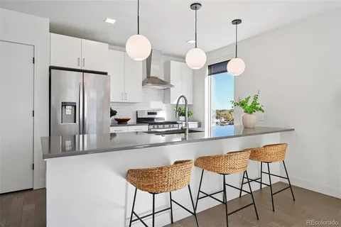 a kitchen with stainless steel appliances kitchen island granite countertop a refrigerator a stove a sink and a dining table with wooden floor