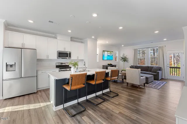 a living room with stainless steel appliances kitchen island granite countertop furniture wooden floor and a view of kitchen