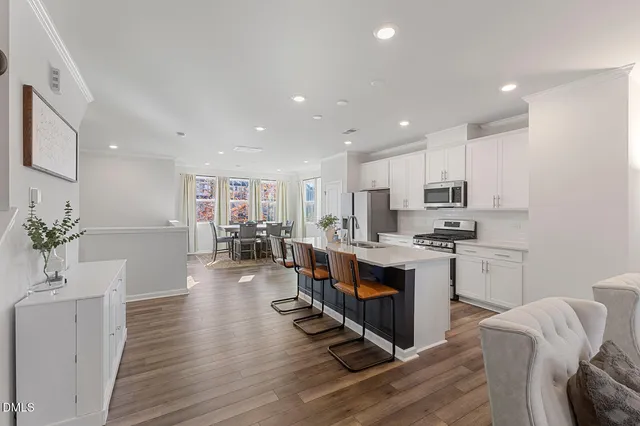 a large white kitchen with wooden floor and stainless steel appliances