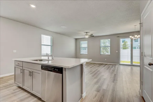 a view of an empty room with wooden floor and a ceiling fan