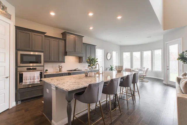 a large kitchen with kitchen island granite countertop a dining table chairs and refrigerator