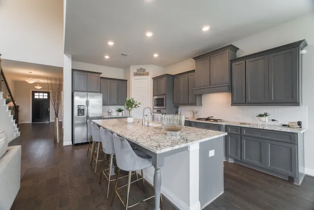 a kitchen with stainless steel appliances granite countertop a table chairs sink refrigerator and microwave