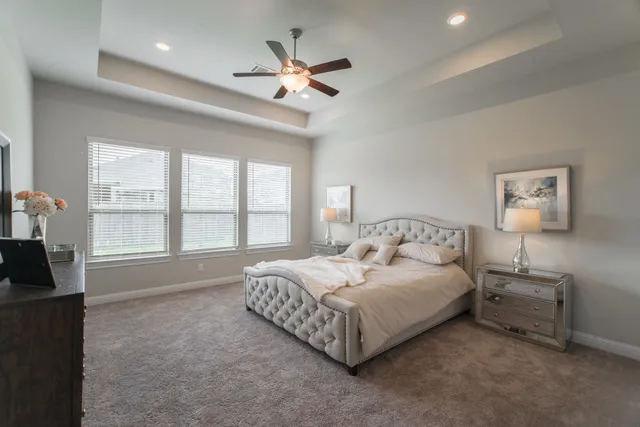 a spacious bedroom with a bed painting on wall and windows