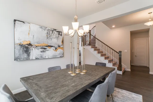 a dining room with wooden floor a chandelier a wooden table and chairs