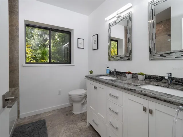 a bathroom with a granite countertop toilet sink and mirror