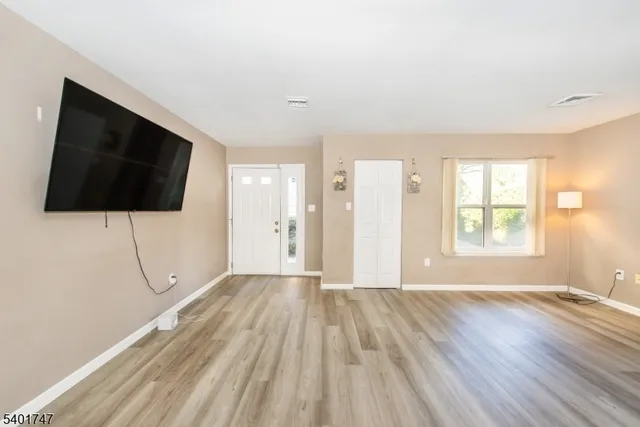 a view of an empty room with wooden floor and windows