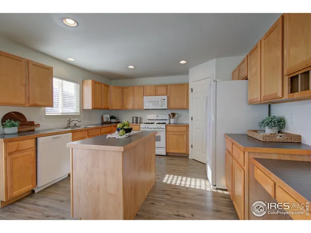 a kitchen with stainless steel appliances granite countertop a refrigerator a sink dishwasher a dining table and chairs with wooden floor