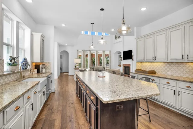 a kitchen with kitchen island granite countertop a stove a sink a center island and living room view
