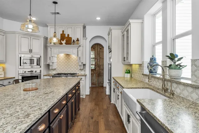 a large kitchen with granite countertop a large counter top cabinets and stainless steel appliances