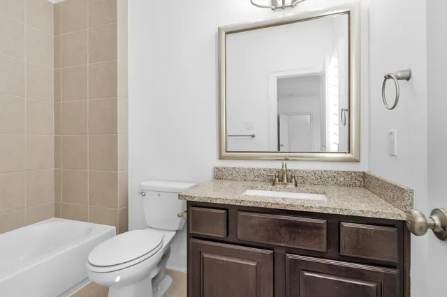 a bathroom with a granite countertop sink toilet and mirror