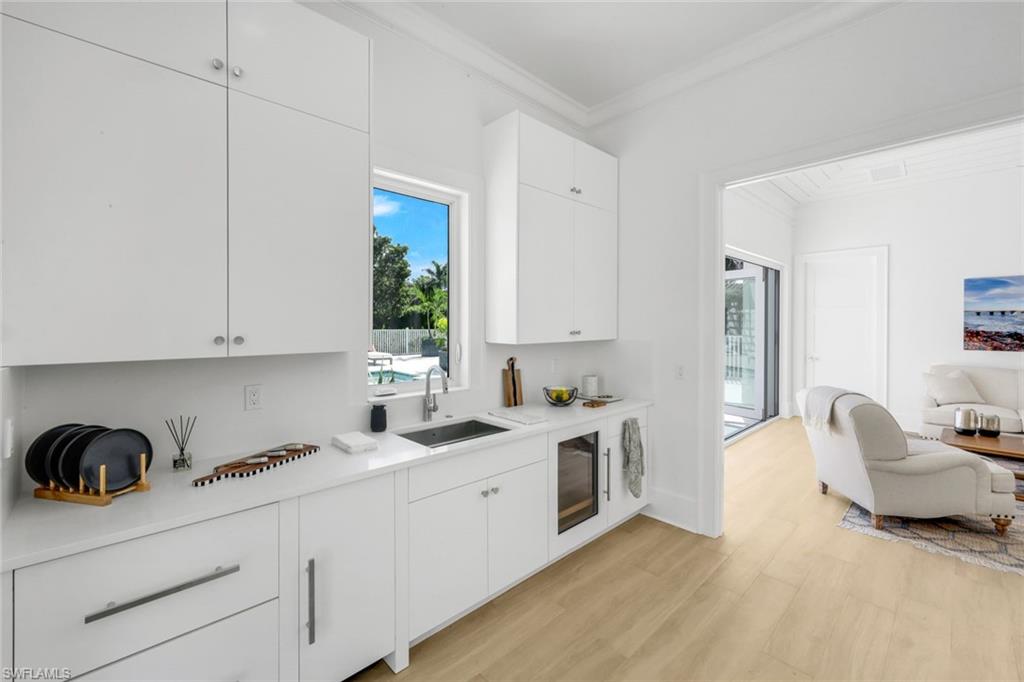 3136 Ravenna Avenue Naples, FL 34120 - Photo 39 of 50 Kitchen with crown molding, light wood-style flooring, plenty of natural light, white cabinets, and modern cabinets