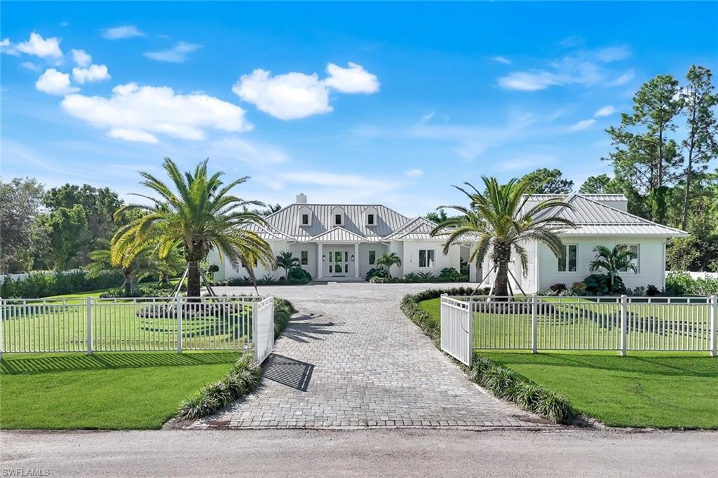 3136 Ravenna Avenue Naples, FL 34120 - Photo 42 of 50 View of front facade with a fenced front yard, curved driveway, and a metal roof