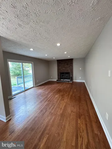 a view of empty room with wooden floor and fireplace