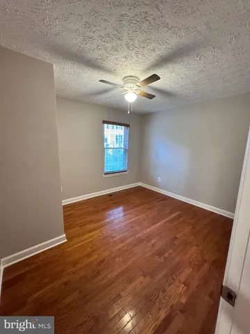 an empty room with wooden floor chandelier and windows