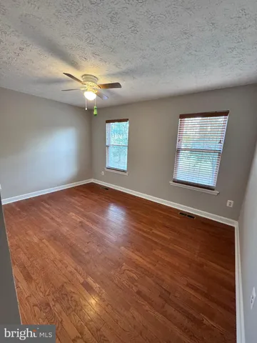 an empty room with wooden floor chandelier and windows