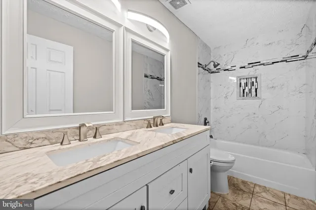 a bathroom with a granite countertop sink a toilet and a bathtub