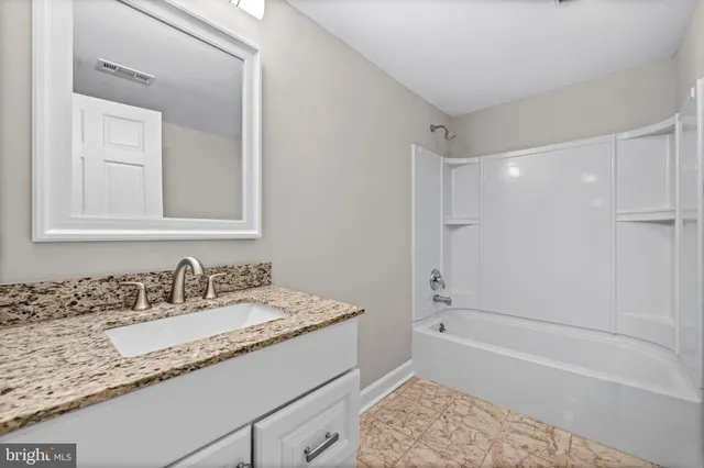 a bathroom with a granite countertop sink a mirror and a bathtub