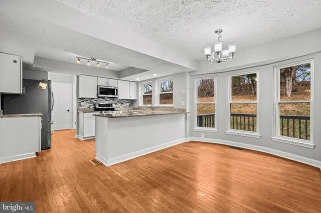 a view of kitchen with granite countertop cabinets stainless steel appliances and wooden floor