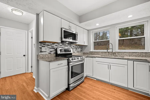 a kitchen with stainless steel appliances granite countertop a stove a sink and a microwave