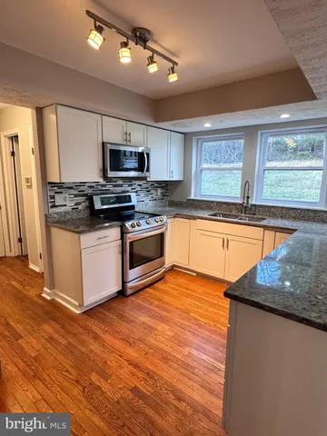 a kitchen with stainless steel appliances granite countertop a stove a sink and a microwave