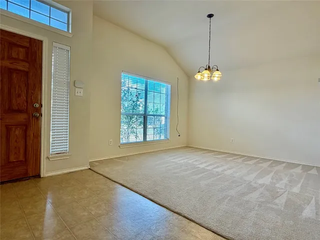 a view of an empty room with window and chandelier fan
