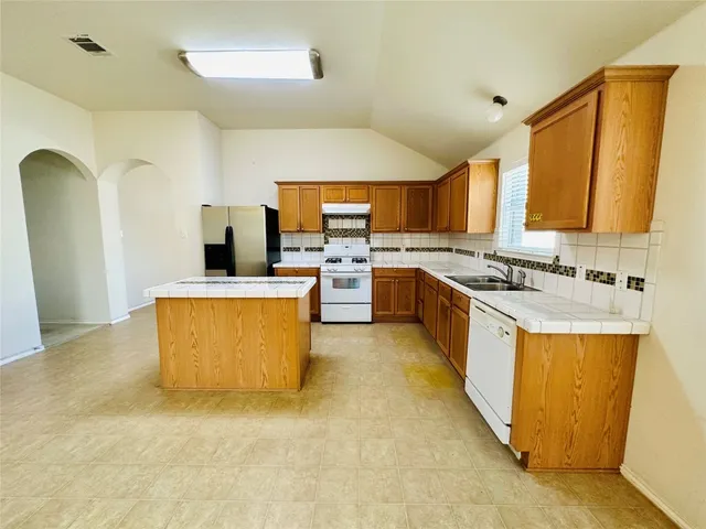a large kitchen with stainless steel appliances granite countertop a stove a sink dishwasher and a refrigerator