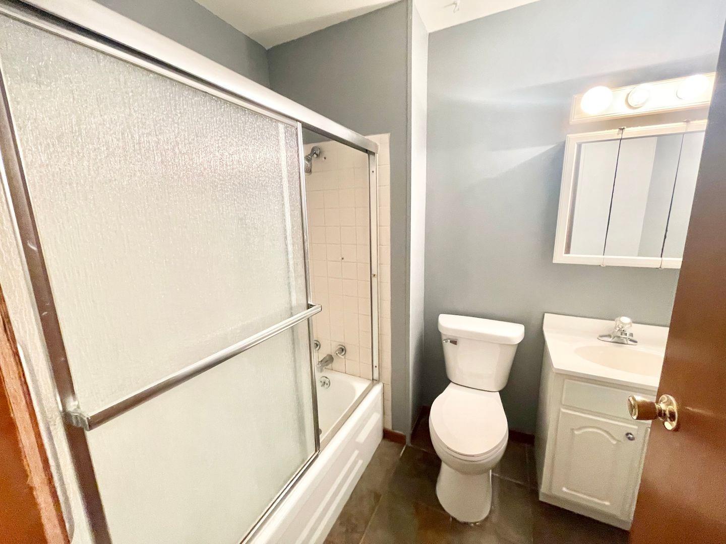 5201 Harrison Street Gary, IN 46410 - Photo 7 of 11 a white toilet sitting next to a bathroom sink and a shower
