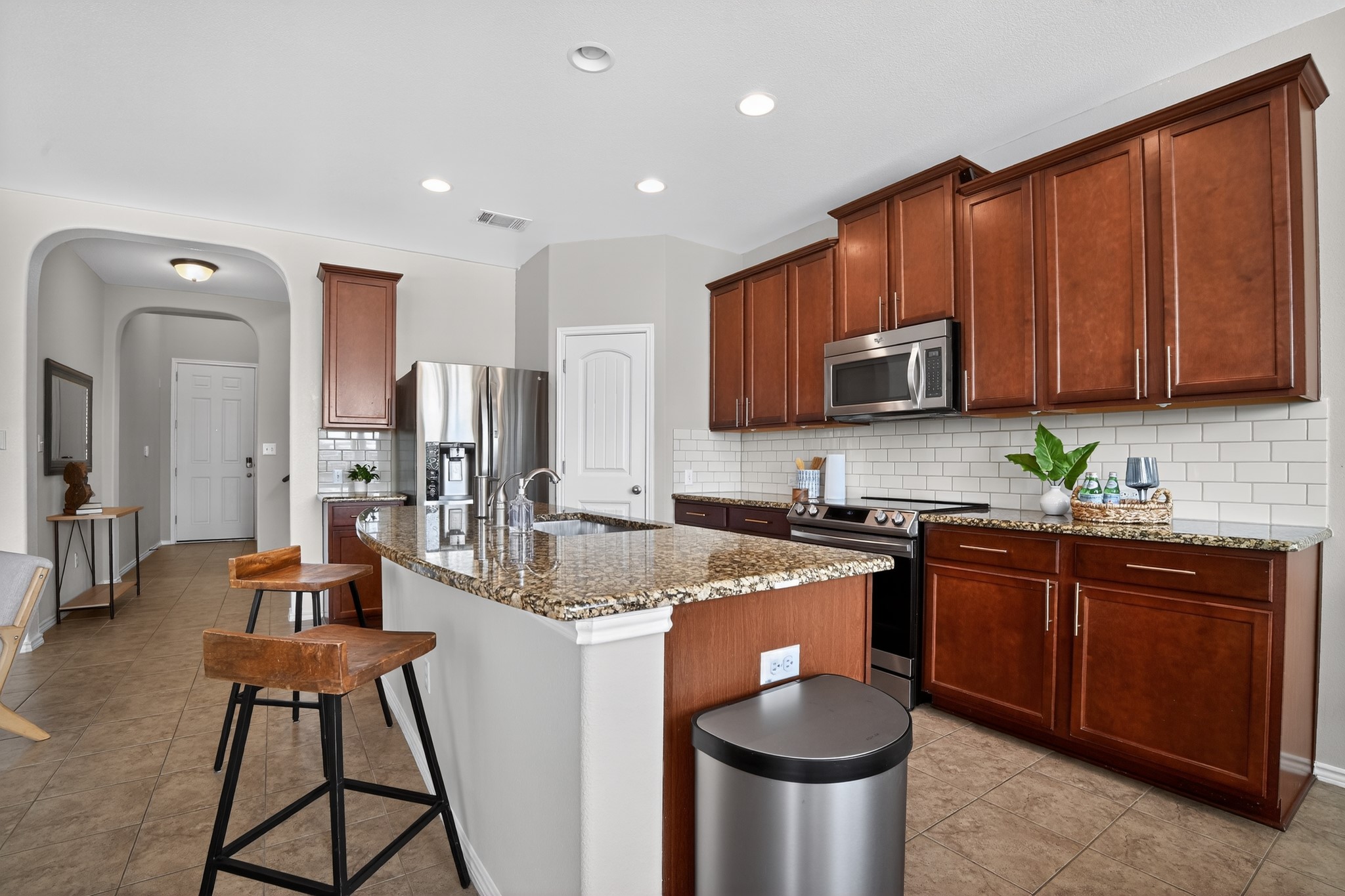 16816 Ruggio Road Pflugerville, TX 78660 - Photo 5 of 30 A well-appointed kitchen features rich wood cabinetry, durable granite counters, and a central island with bar seating.