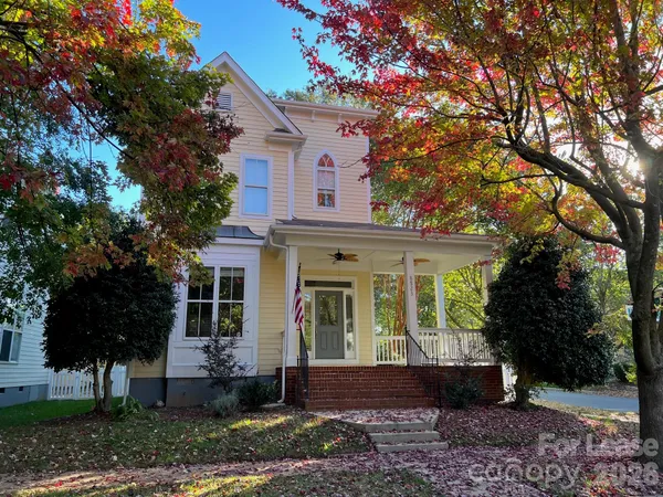 a view of a white house next to a yard with plants and trees