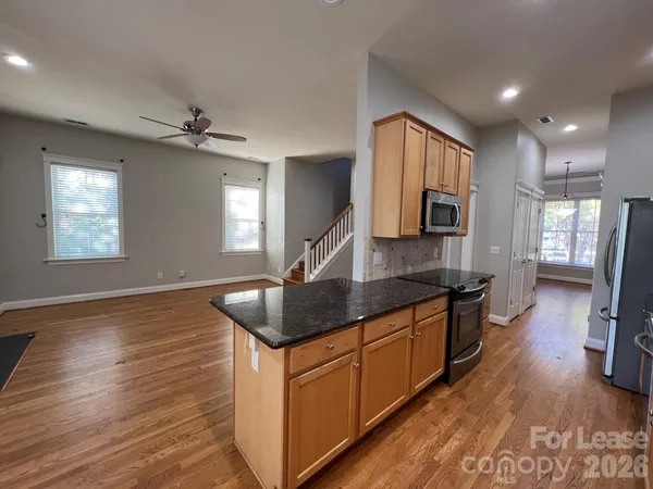 a kitchen with stainless steel appliances granite countertop a sink a refrigerator and wooden cabinets
