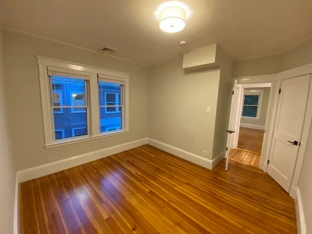 a view of an empty room with wooden floor and windows